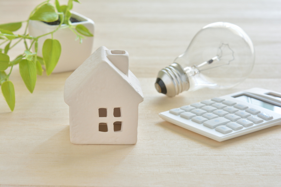 家の模型と電卓（省エネ住宅のイメージ画像）